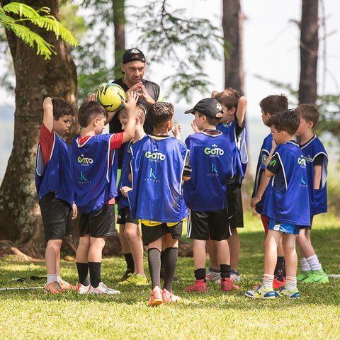 Roda de crianças com o treinador antes do treino